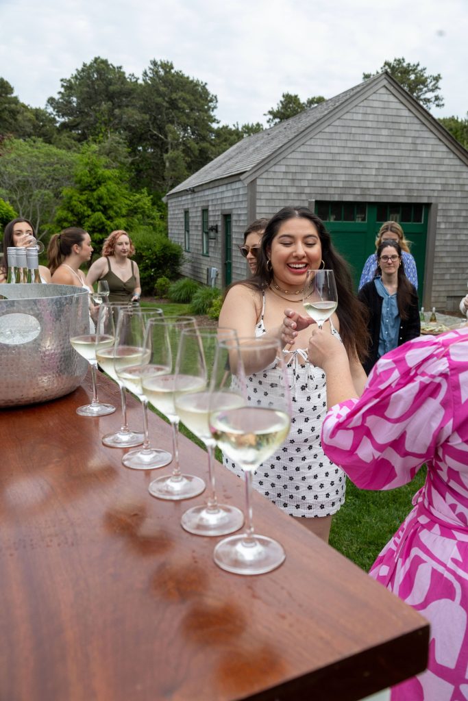 A smiling woman cheersing with someone off camera at a wine tasting