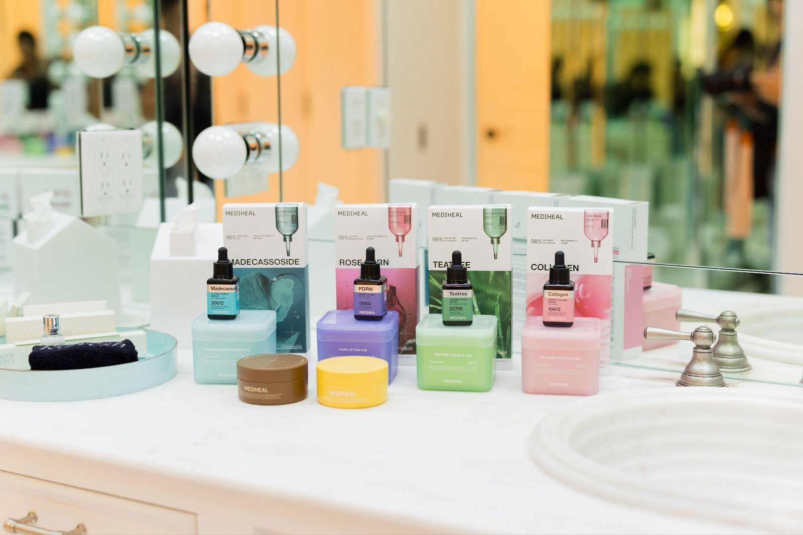 Mediheal skincare products — serums, masks, and pads in colorful packaging — displayed on a bathroom counter with mirror reflection at CBC's Holiday House in Stowe, Vermont