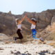 Two woman jumping and high-fiving in the Palm Spring desert, during CBC FIT House