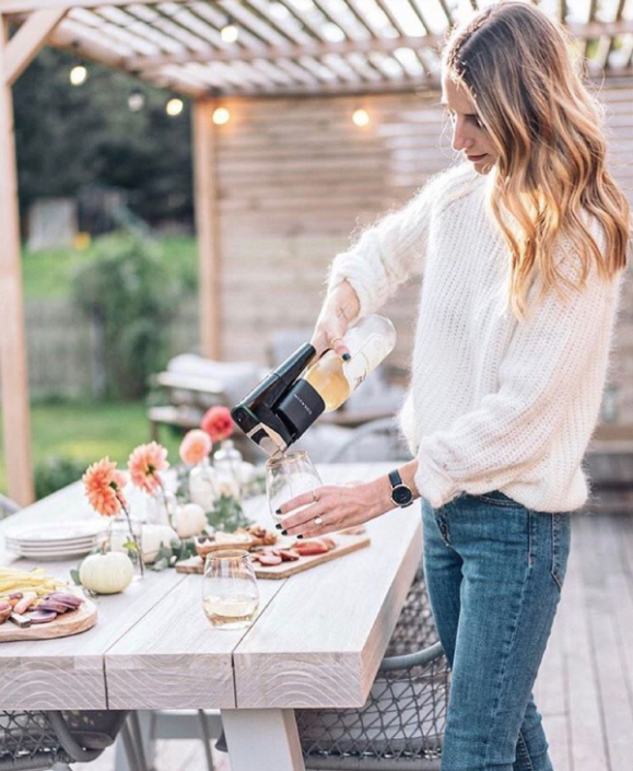 Influencer using a Coravin system to pour a glass of wine