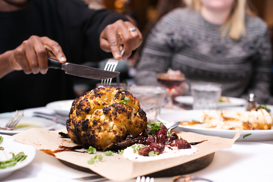 person at dinner cutting into cauliflower