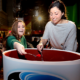Couple women dipping spoons into Ocean Spray's world's largest can of cranberry sauce