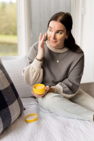 Editor sitting on bed and applying Mediheal face cream to her cheek at CBC's Holiday House press trip in Stowe, Vermont