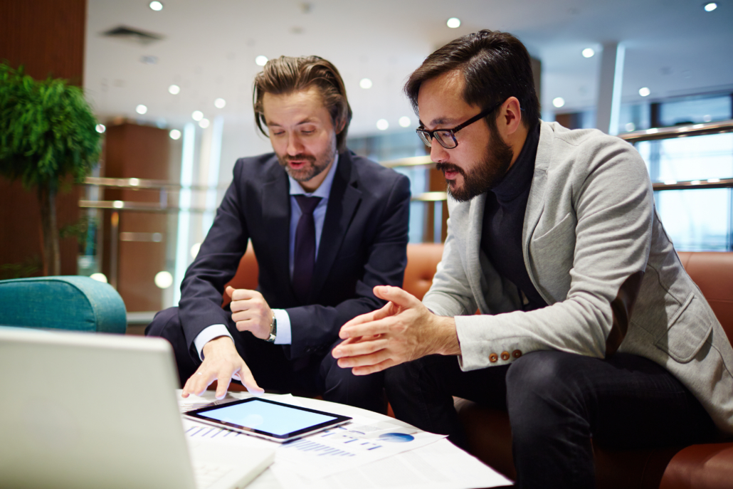 Serious business partners discussing data in touchpad